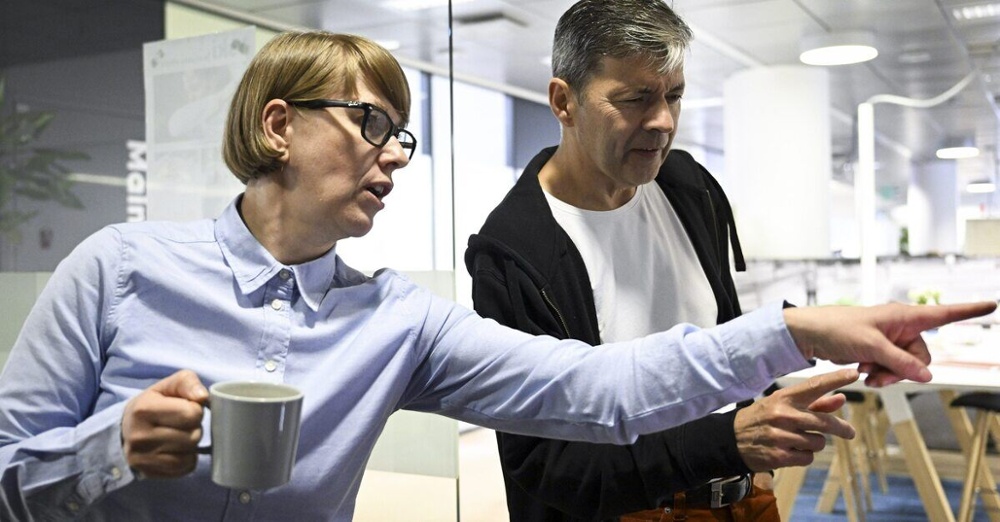 Nainen ja mies tarkastelevat kahviautomaattia konttorilla